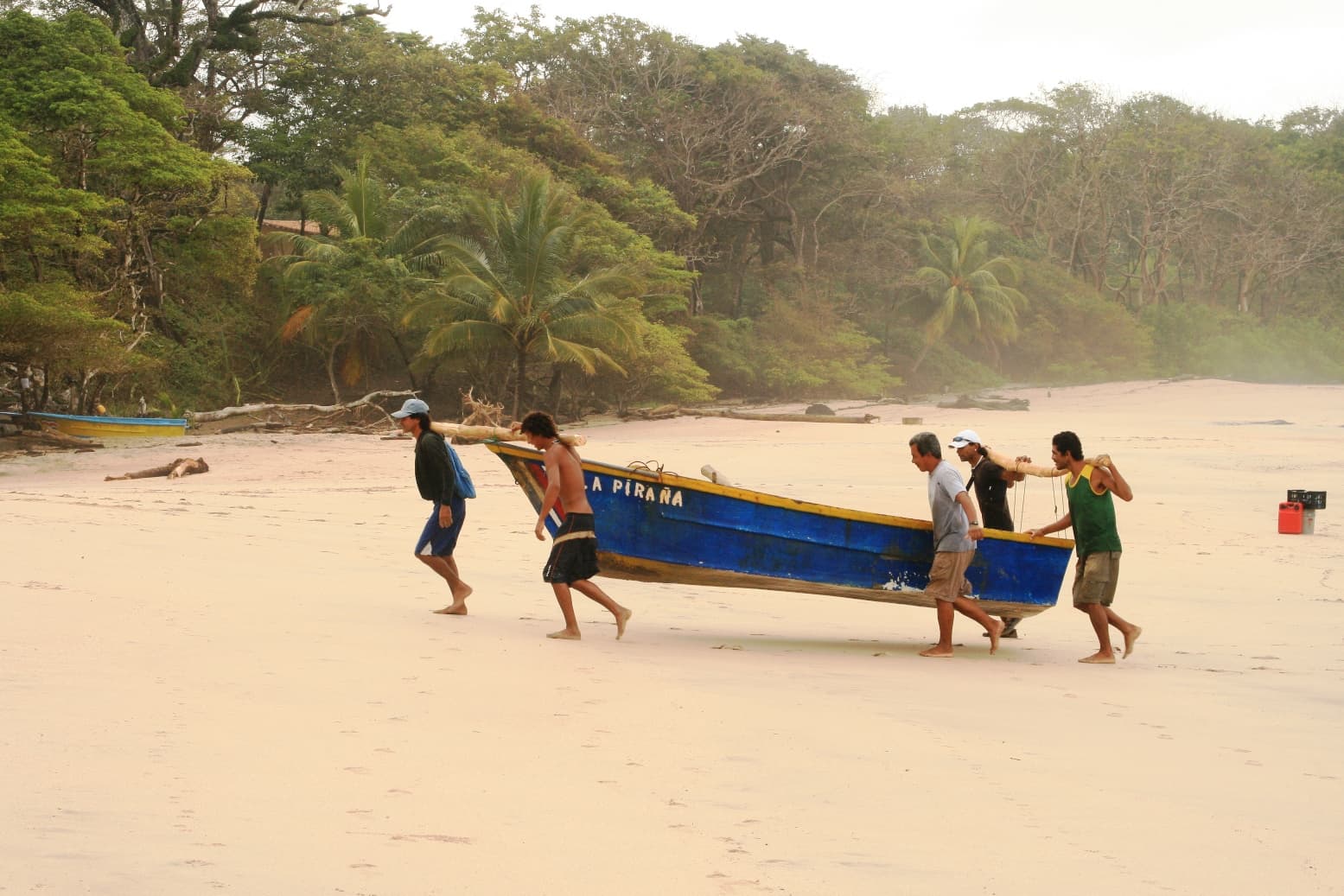 Fishermen carrying a boat up the sand at Playa Nosara — Nosara, Costa Rica
